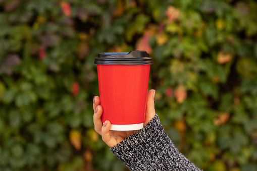 Cup with coffee in a female hand, bokeh.