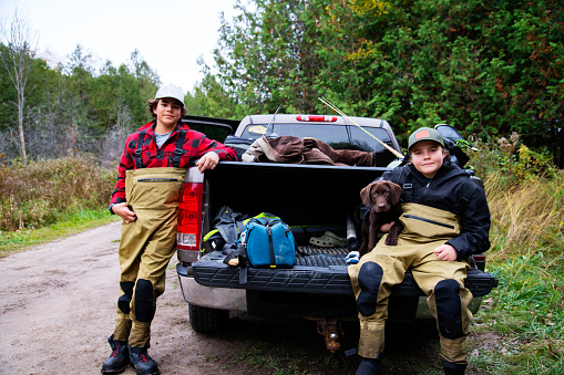 Fishing trip with a chocolate labrador puppy.  Two brothers getting ready to go fishing with their lab puppy.