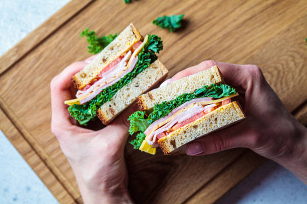 istock Sandwiches with ham, cheese, vegetables and kale in hands, top view. 1281065251