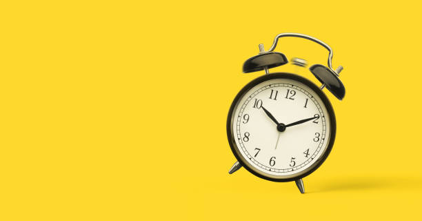 close up of alarm clock isolated on yellow background - timing is everything imagens e fotografias de stock