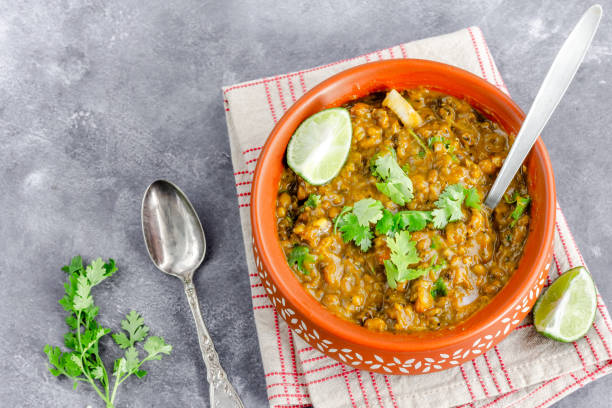 tradicional lentilha indiana sup / dahl, guarnecido com cebola, coentro, limão e pimentão verde, comida vegana saudável, vista superior, fundo cinza - 6723 - fotografias e filmes do acervo