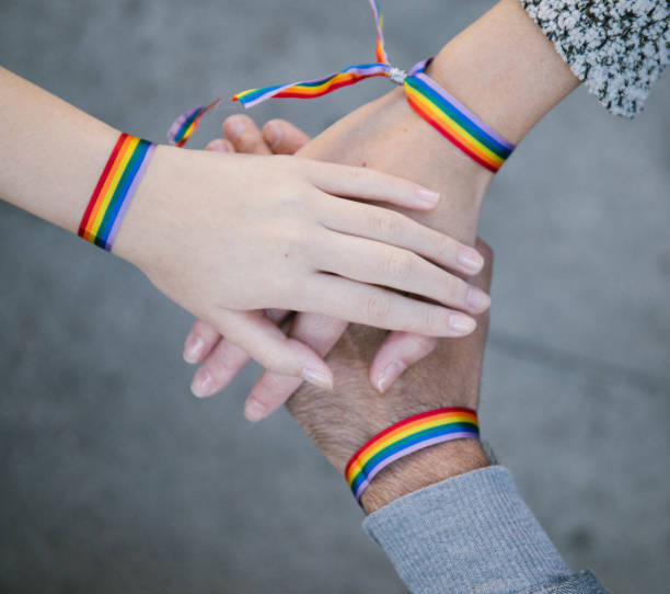 istock Homosexual people in rainbow bracelets stacking hands 1281071791