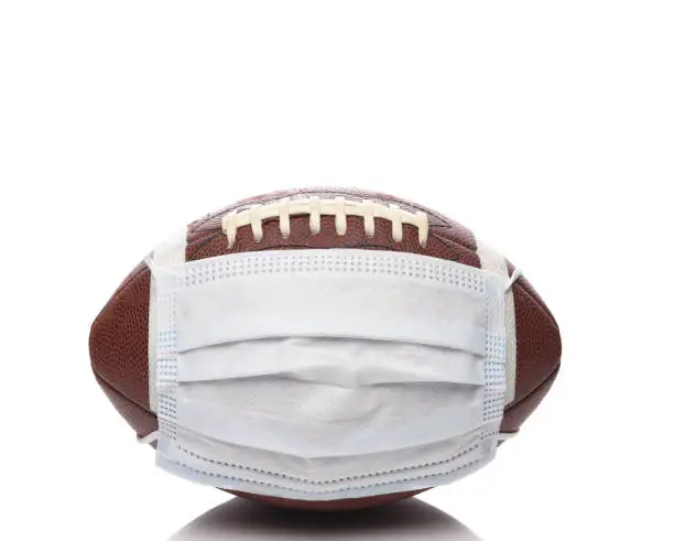 Sports and Covid-19 Concept.  An american Foortball with a surgical mask.