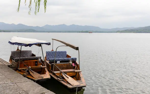Photo of Two tethered traditional wooden boats with paddles for tourist excursions on West Lake