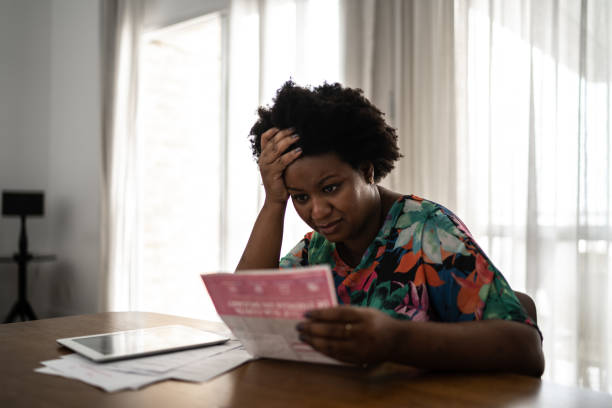 femme inquiète recherchant des factures financières à la maison - struggle photos et images de collection