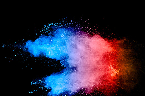 Multicolored powder explosion on black background. Blue pink and orange dust splashing.