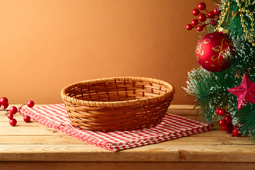 Empty basket on wooden table with tablecloth and Christmas tree. Christmas background for mock up design