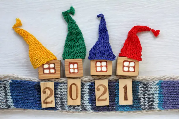 yellow, green, blue, red hats are worn on wooden houses standing on a knitted scarf