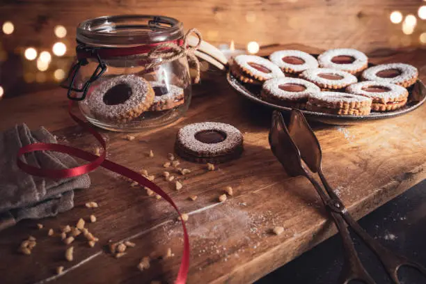 Homemade traditional linzer cookies with strawberry jam. Atmospheric christmas still life with golden bokeh and space for text.