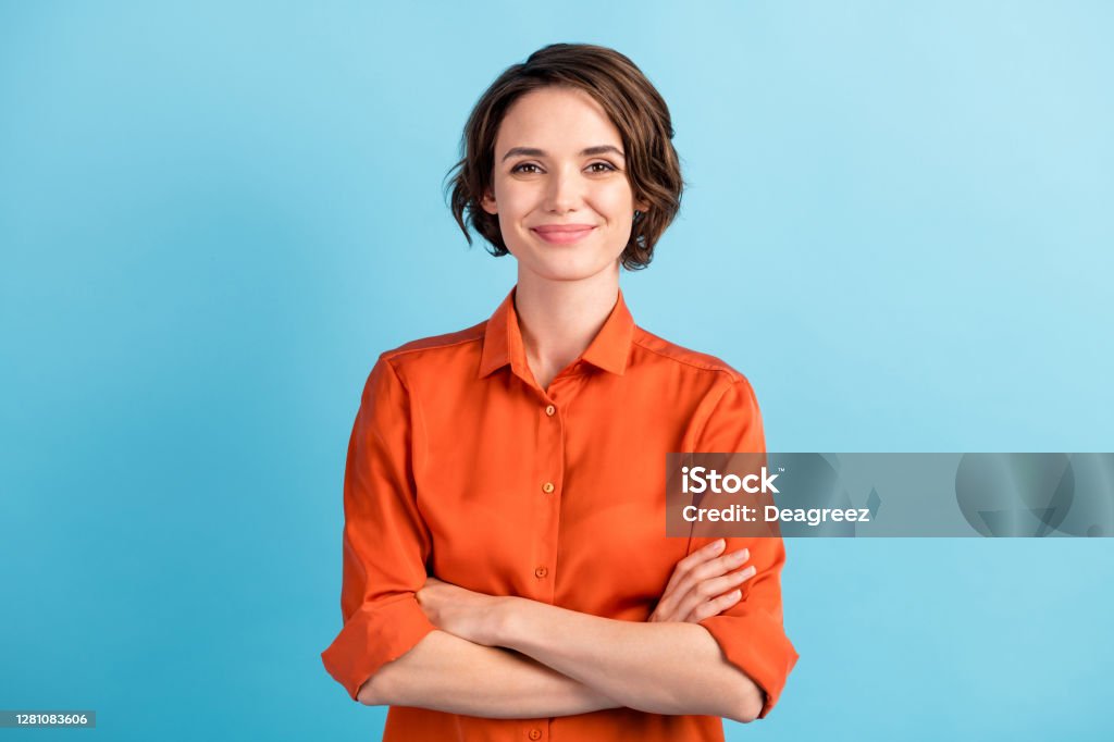Photo of attractive charming lady cute bobbed hairdo arms crossed self-confident person worker friendly smile good mood wear orange office shirt isolated blue color background Photo of attractive charming lady cute bobbed hairdo arms crossed, self-confident person worker friendly smile good mood wear orange office shirt isolated blue color background One Woman Only Stock Photo