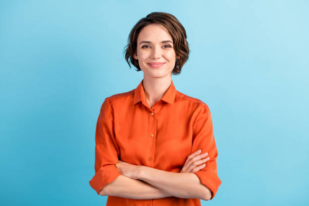 Photo of attractive charming lady cute bobbed hairdo arms crossed self-confident person worker friendly smile good mood wear orange office shirt isolated blue color background Photo of attractive charming lady cute bobbed hairdo arms crossed, self-confident person worker friendly smile good mood wear orange office shirt isolated blue color background white people stock pictures, royalty-free photos & images