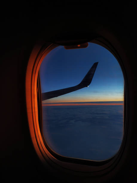view from the airplane window flying over the sea at sunset - wing airplane window sunset imagens e fotografias de stock