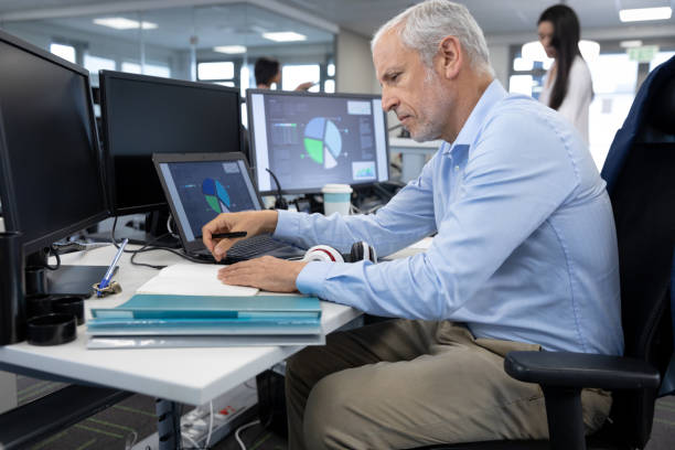 istock Senior businessman reading documents while sitting on his desk at modern office 1281085352