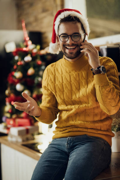 istock Cheerful man talking on the phone while celebrating Christmas at home. 1281086027