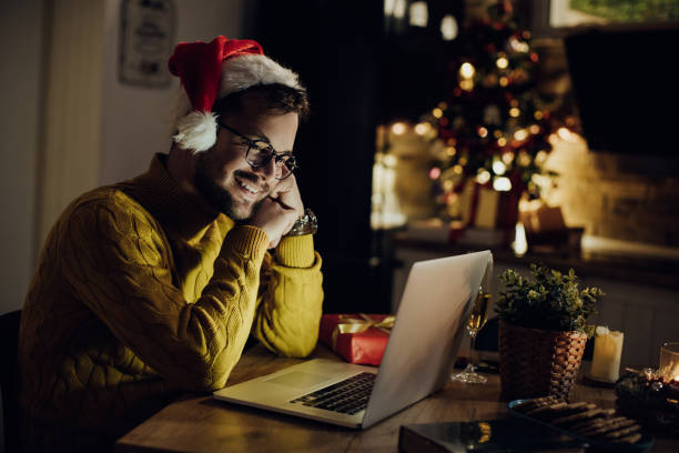 istock Young smiling man using laptop on Christmas Eve at home. 1281087498