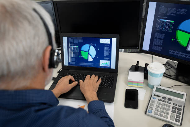 istock Senior businessman wearing headset using laptop at modern office 1281087641