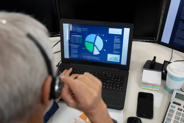 istock Senior businessman wearing headset using laptop at modern office 1281087716