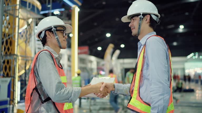 Two engineer man shaking hands in factory