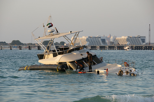Dubai, United Arab Emirates - January 5, 2019: Sunken yacht near the Ferris wheel in Dubai. Rescue work on raising the sunken yacht
