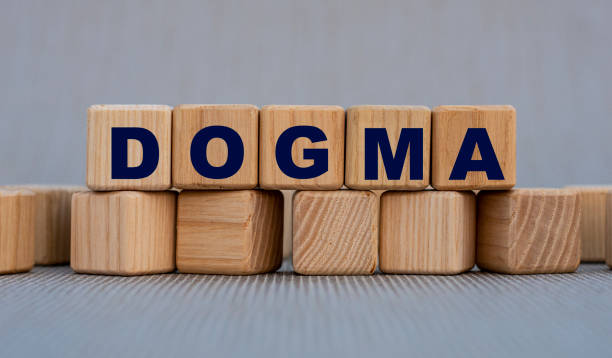 dogma - wort auf holzwürfeln auf einem schönen grauen hintergrund - dogma stock-fotos und bilder