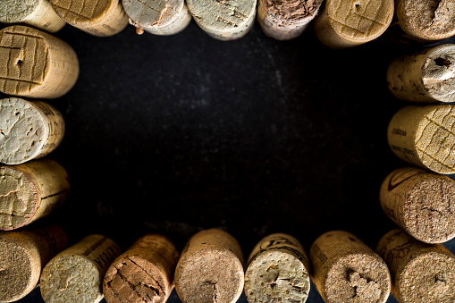 Wine bottle with broken cork on gray background. A bottle of red wine is sealed with half a broken cork.