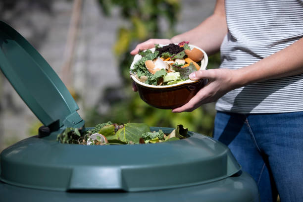 fermez-vous vers le haut de la femme vidant le gaspillage de nourriture dans le composteur de jardin à la maison - poubelles photos et images de collection