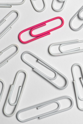 White and pink paper clips over white background.