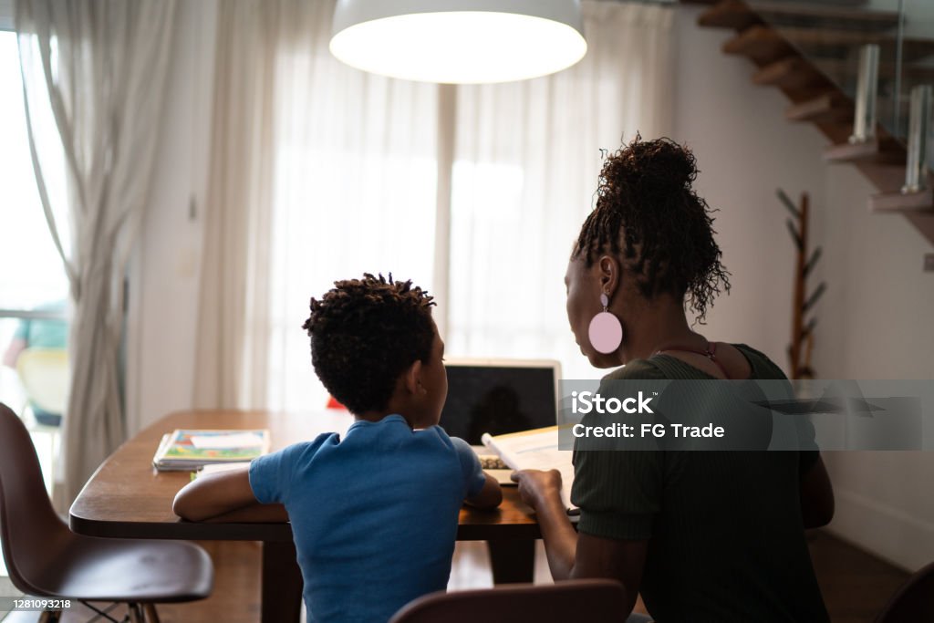 Rear view of mother and son studying at home Rear View Stock Photo