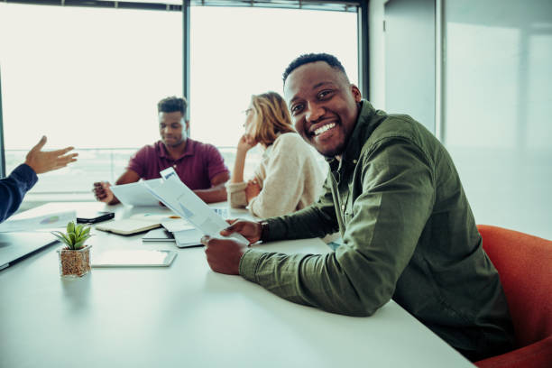 istock Mixed race business man smiling working through paperwork with parters sitting around table in conference room 1281094027