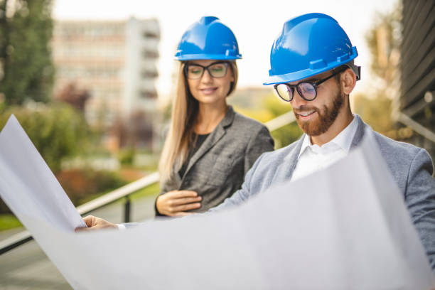 istock Two civil architects wearing helmet, reading document and checking new project outdoors 1281094052