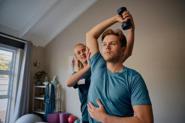 istock Physiotherapist instructing male patient correct exercise form with dumbbells 1281097014