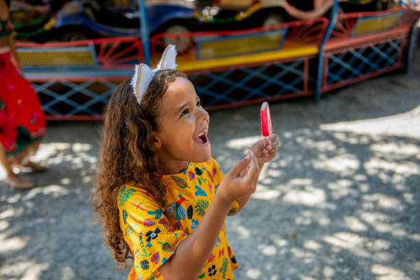 Happy girl eats ice cream Little girl having fun at amusement park carnival children stock pictures, royalty-free photos & images
