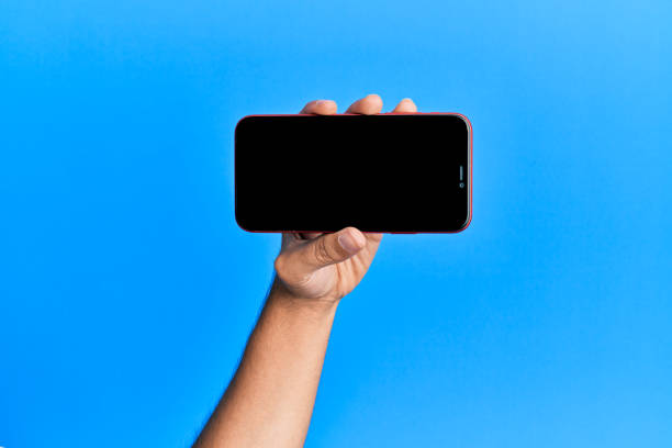 istock Hand of young hispanic man showing smartphone over isolated blue background. 1281100539