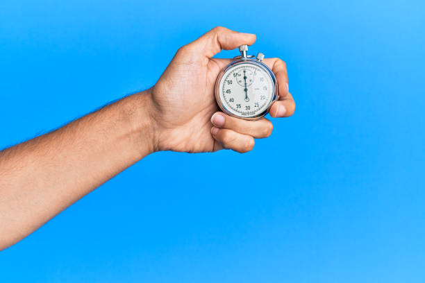 Hand of young hispanic man using stopwatch over isolated blue background. Hand of young hispanic man using stopwatch over isolated blue background. stopwatch photos stock pictures, royalty-free photos & images