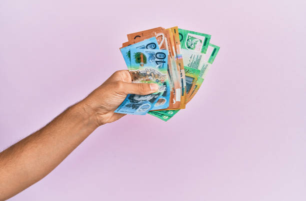 istock Hispanic hand holding australian dollars banknotes over isolated pink background. 1281101450