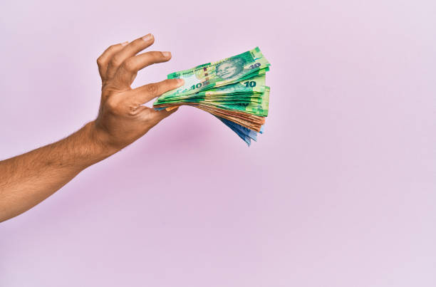 Hispanic hand holding south africa rands banknotes over isolated pink background. Hispanic hand holding south africa rands banknotes over isolated pink background. african currency stock pictures, royalty-free photos & images