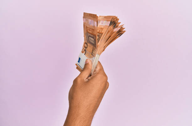 istock Hispanic hand holding 50 euro banknotes over isolated pink background. 1281101614