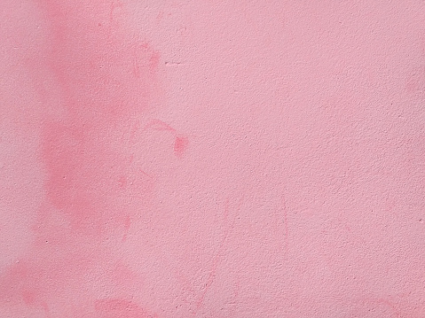 Rough wall background, painted with pink paint. Abstract texture. Can be used for layout or placement of text and images. Close-up. Detail of architecture, construction and masonry.