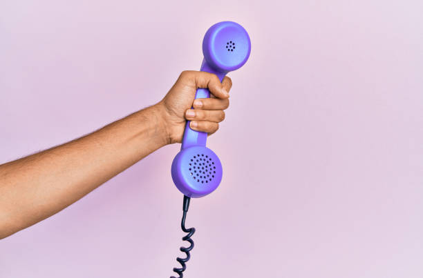 istock Hispanic hand holding vintage telephone over isolated pink background. 1281101695