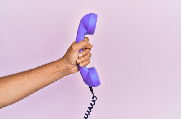 istock Hispanic hand holding vintage telephone over isolated pink background. 1281101702