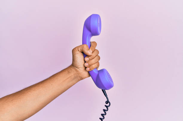 istock Hispanic hand holding vintage telephone over isolated pink background. 1281101714