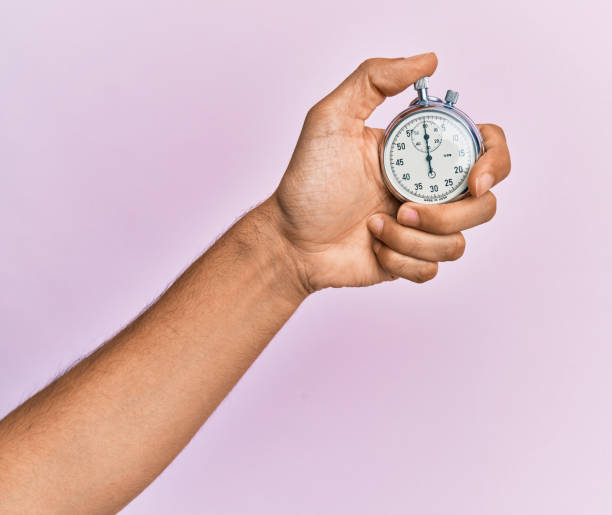 istock Hand of young hispanic man using stopwatch over isolated pink background. 1281101715