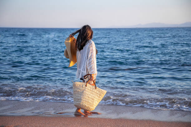 istock Beautiful boho model in a hat with a wicker bag on the beach 1281102059