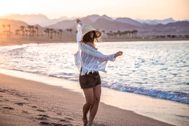 istock Woman at sunset on the beach in a hat. 1281102066