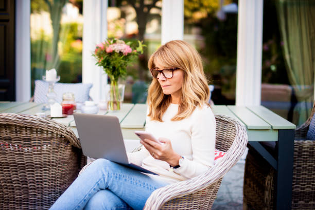 istock Mature woman sitting on terrace while working from home 1281102234