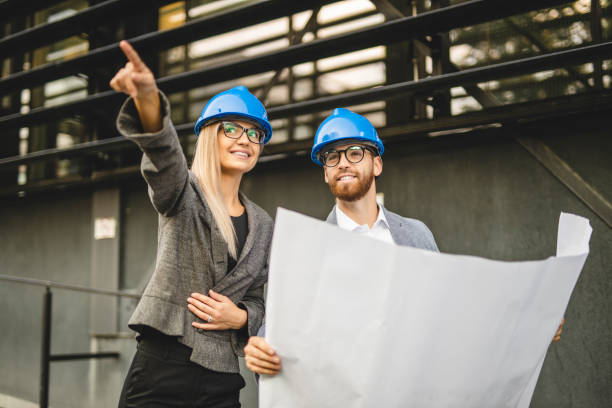 istock Two civil architects wearing helmet, reading document and checking new project outdoors 1281102489