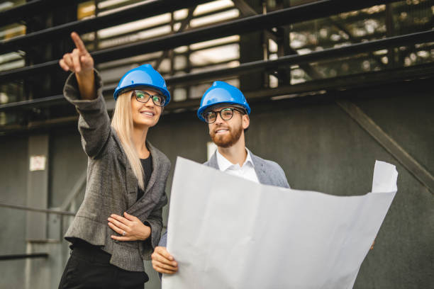 istock Two civil architects wearing helmet, reading document and checking new project outdoors 1281103066