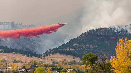 BOULDER, CO, USA - OCTOBER 17, 2020: An Erickson Aero Tanker MD-87 drops fire retardant on the Cal Wood fire burning northwest of Boulder, Colorado with nearby homes under threat from the largest wildfire in Boulder County history.