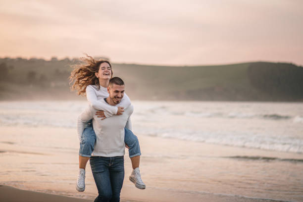 istock Young couple walking piggyback on a beach at sunset 1281104951