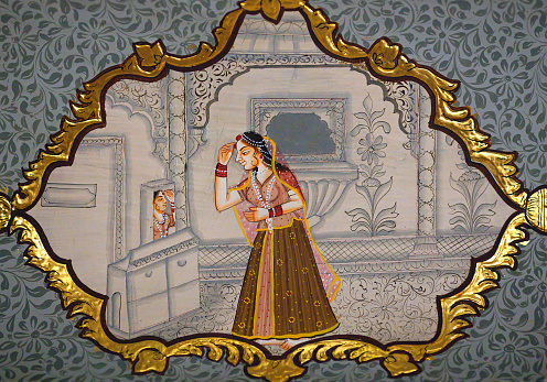 Jaisalmer, Rajasthan state, India - January 8, 2020: Indian woman in dressing room - ancient wall painting miniature of Patwon Ki Haveli. A haveli is a traditional townhouse or mansion in India.